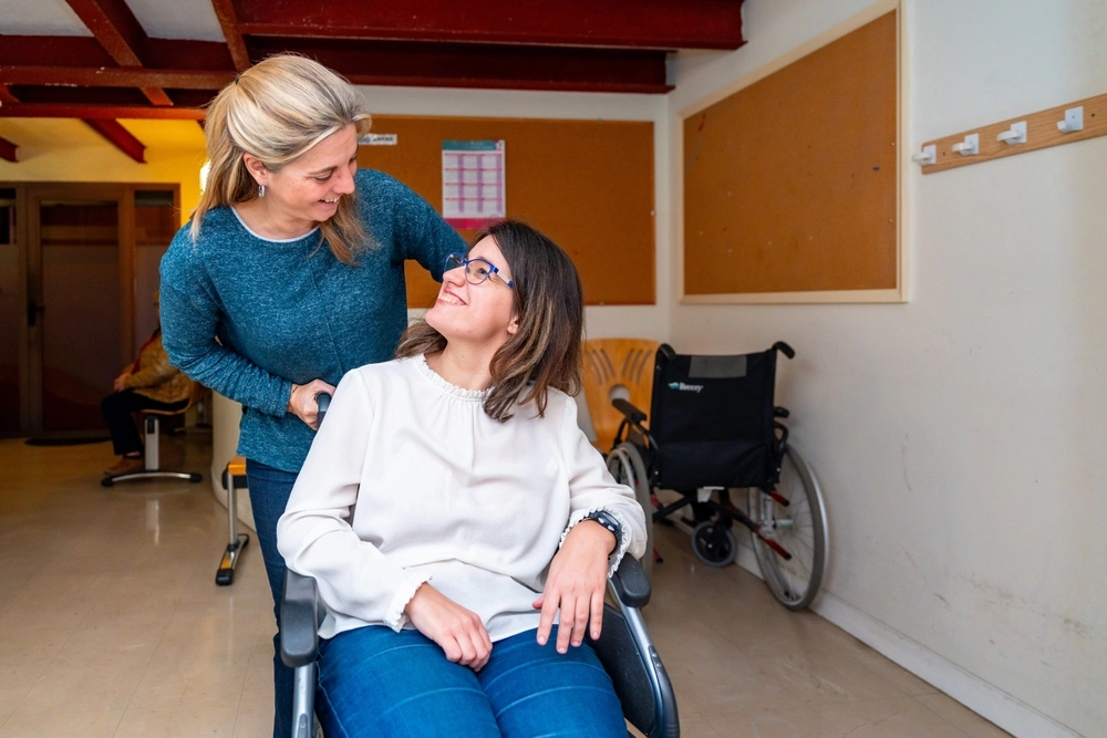 Disabled women looking at carer while sitting on a wheelchair